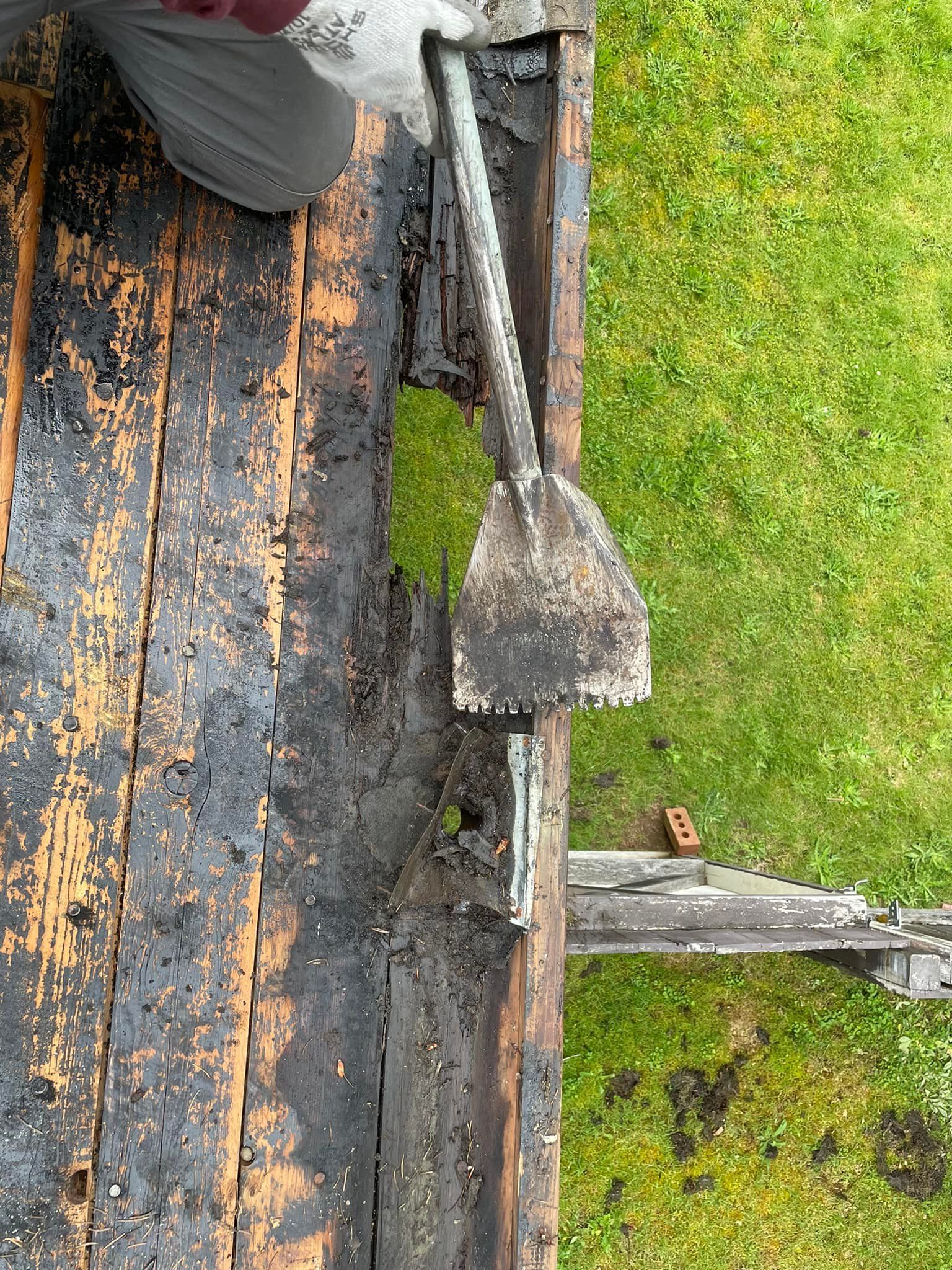 A person is holding a shovel on top of a wooden deck.