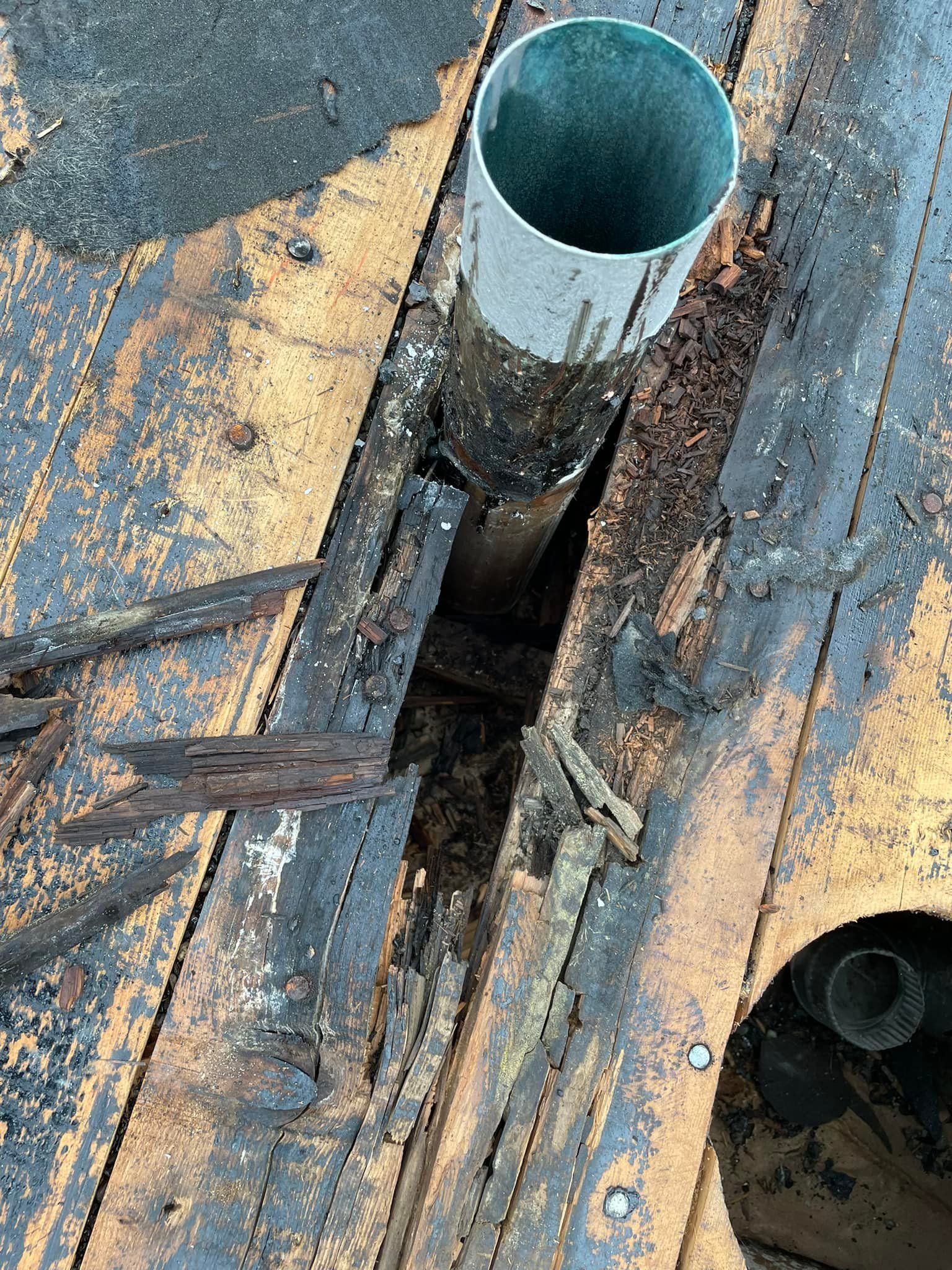 A metal pipe is sticking out of a hole in a wooden deck.