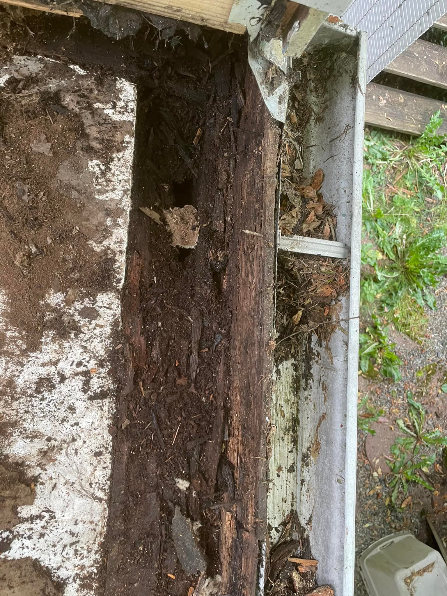 A close up of a wooden beam with a gutter in the background.