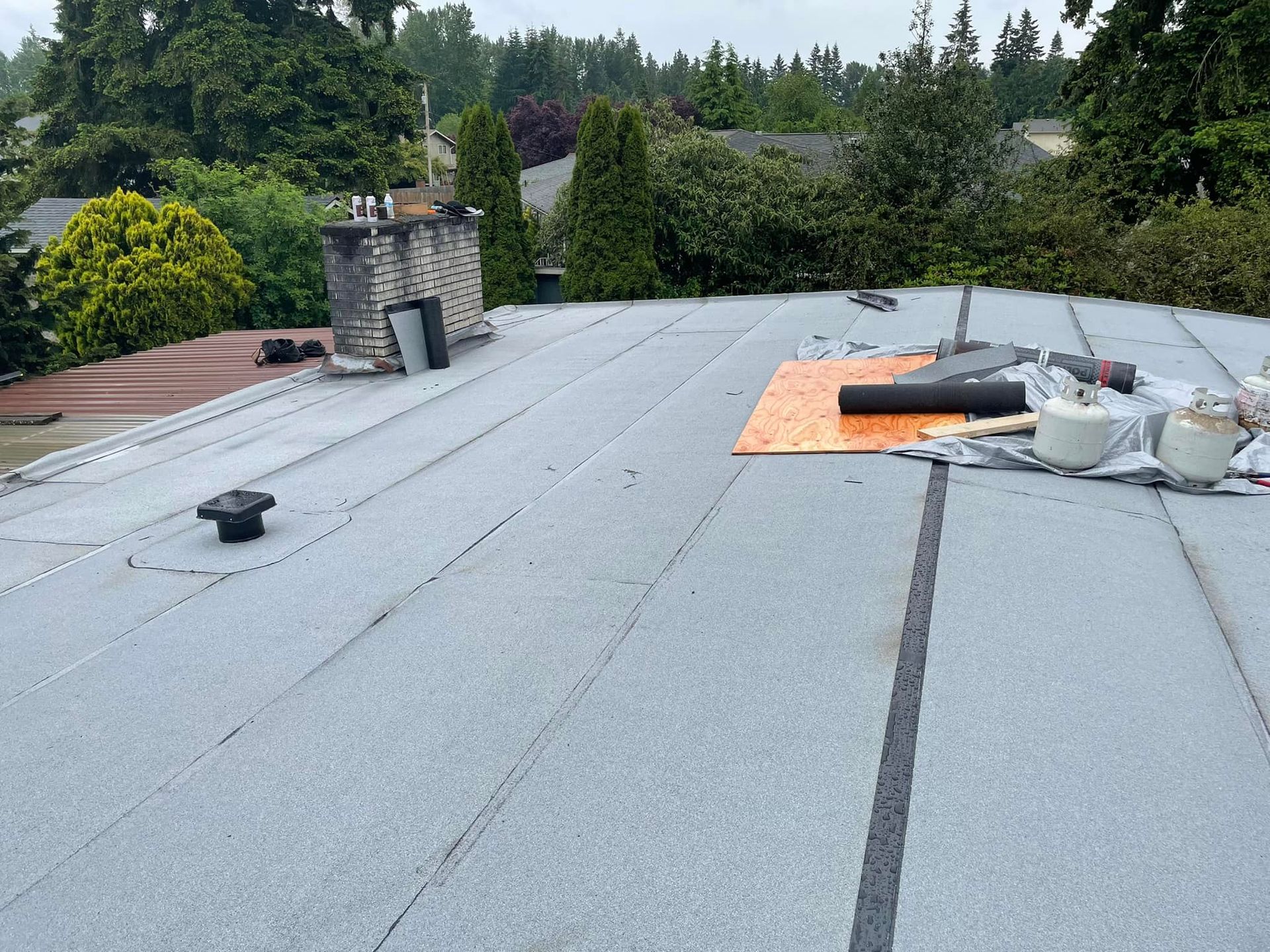 A roof with a chimney and trees in the background