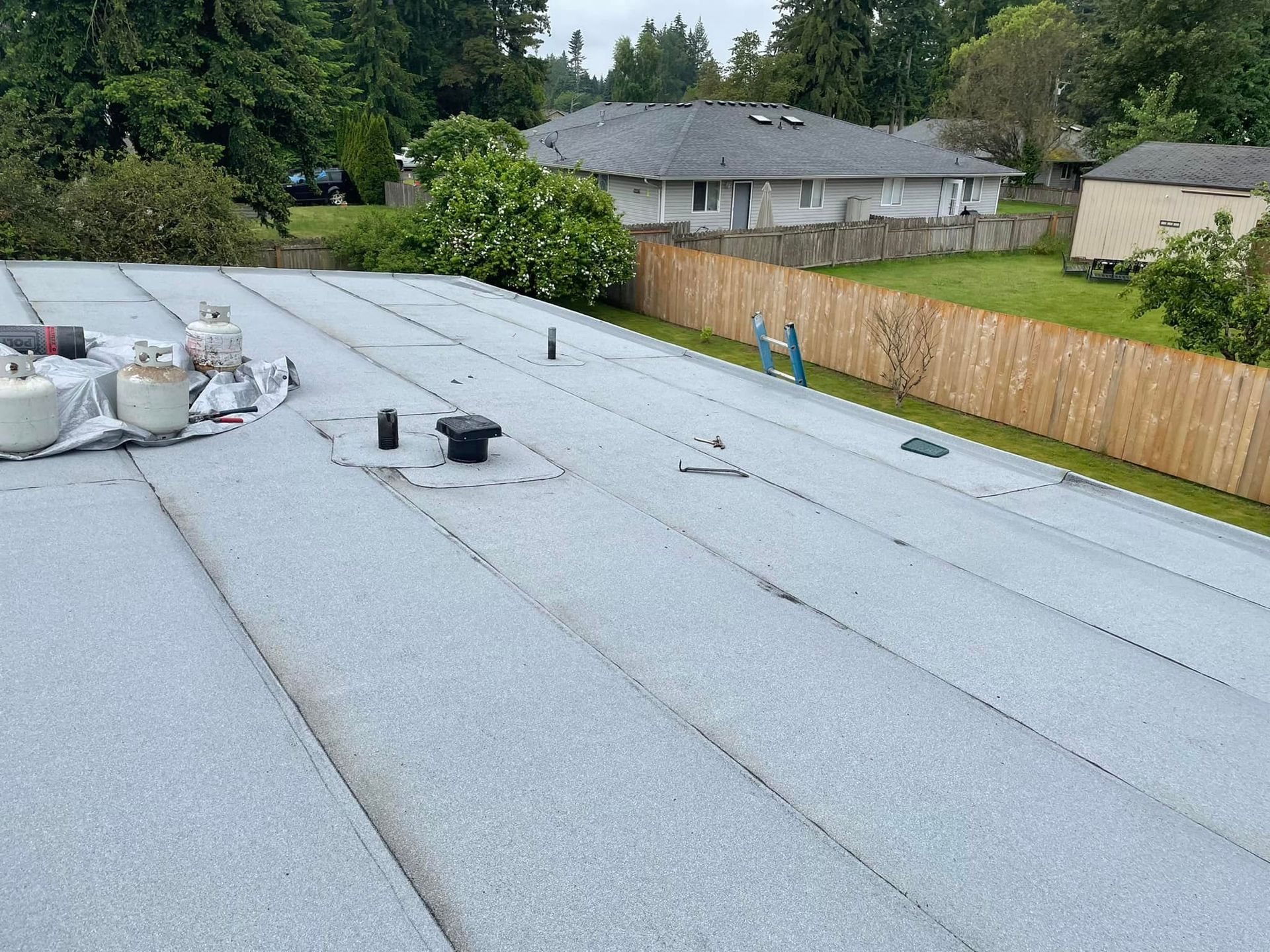 A roof with a wooden fence in the background and a house in the background.