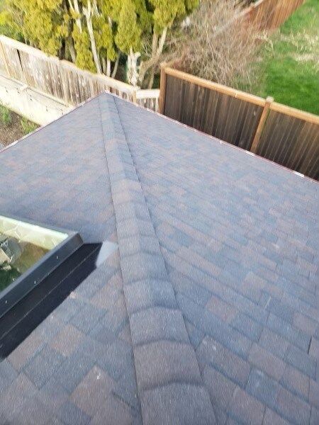 A roof with a skylight on it and a fence in the background.