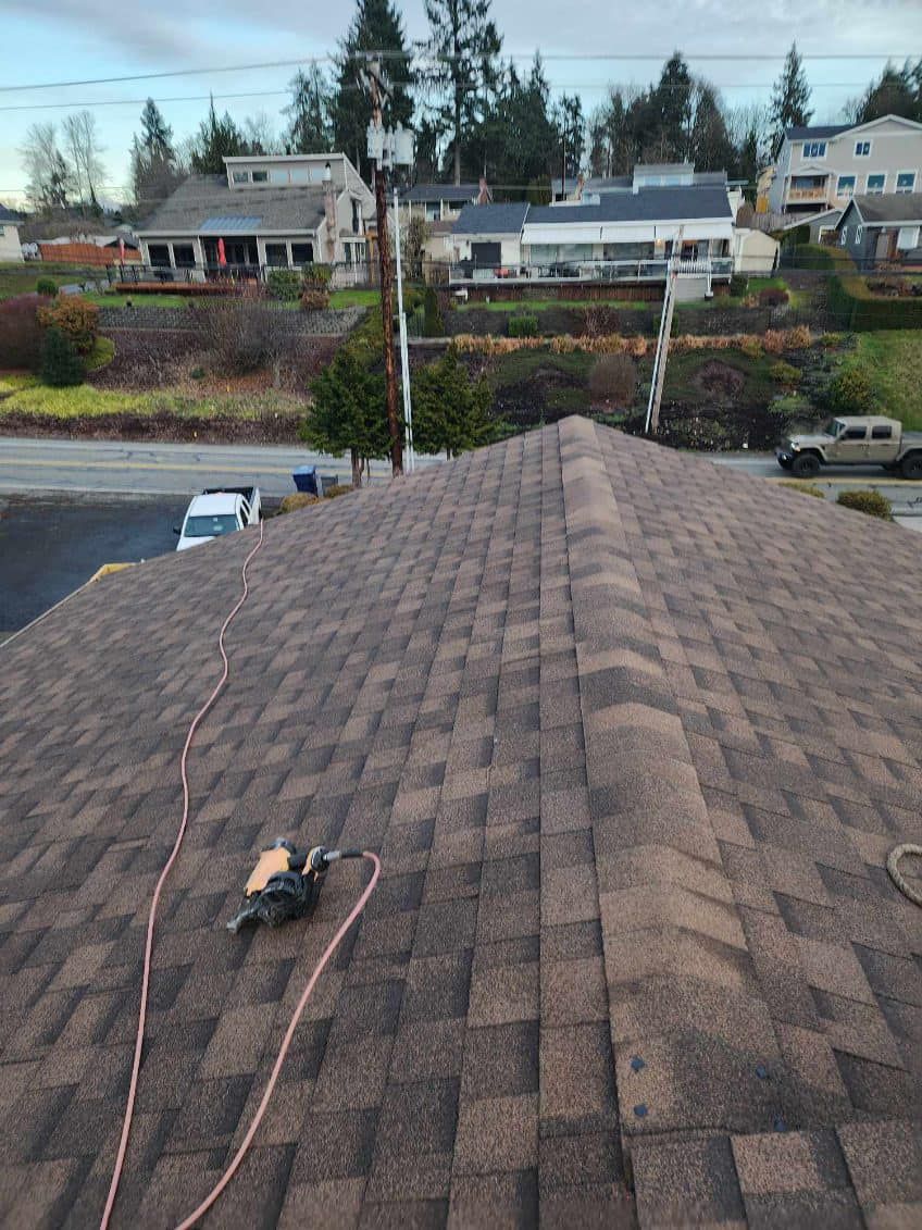 A person is standing on top of a roof with a tool on it.