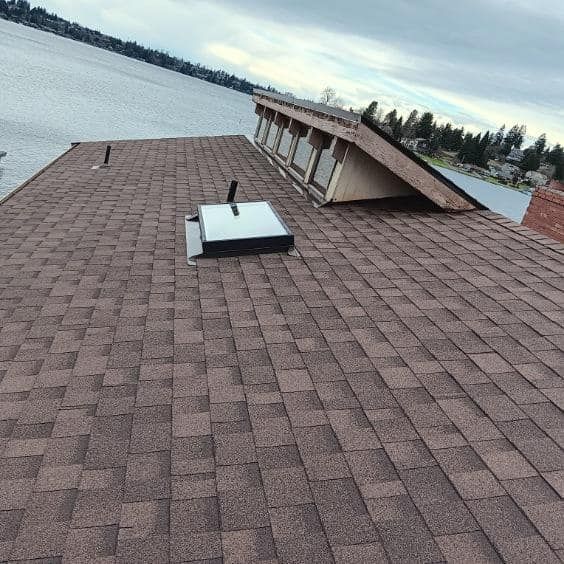 A roof with a skylight on it overlooking a body of water