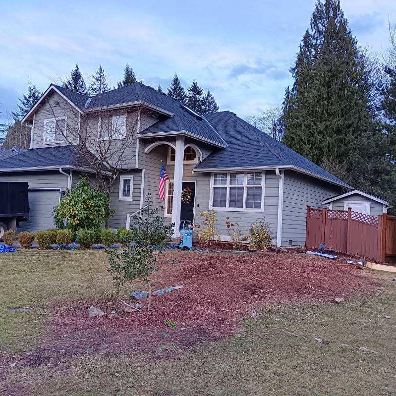 A large house with a blue roof and a red fence in front of it.