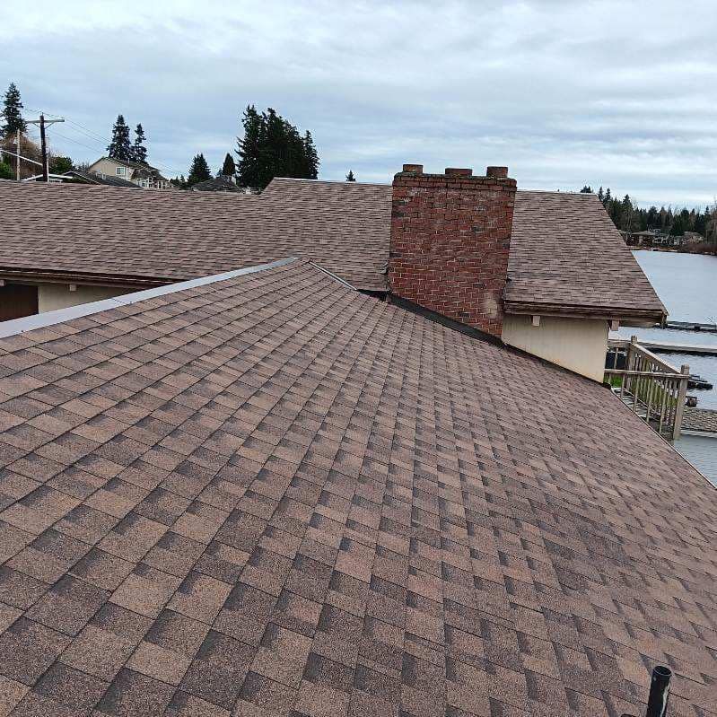 A roof with a chimney on it and a river in the background.