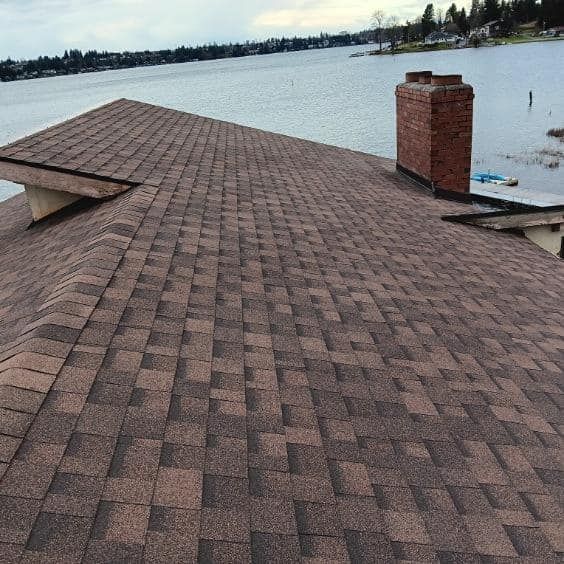 A roof with a chimney on it overlooking a body of water.