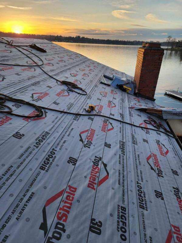 A roof with a chimney and a sunset in the background.