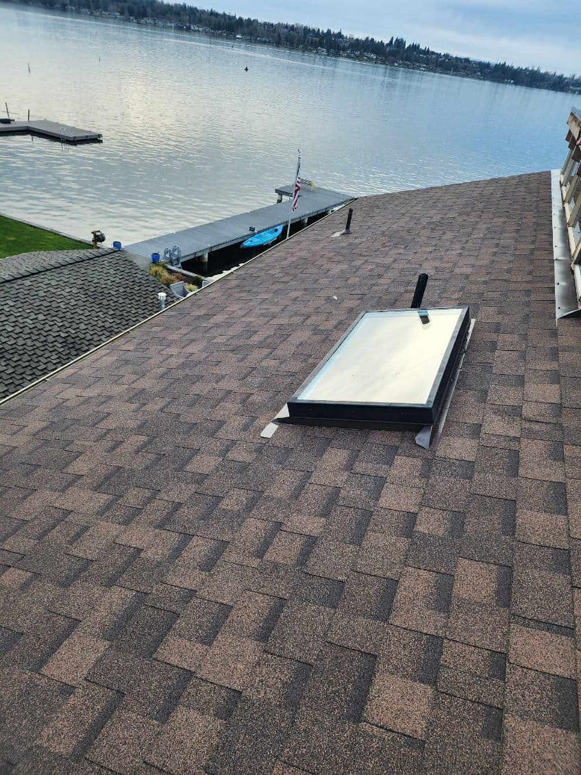 A roof with a skylight and a view of a lake.