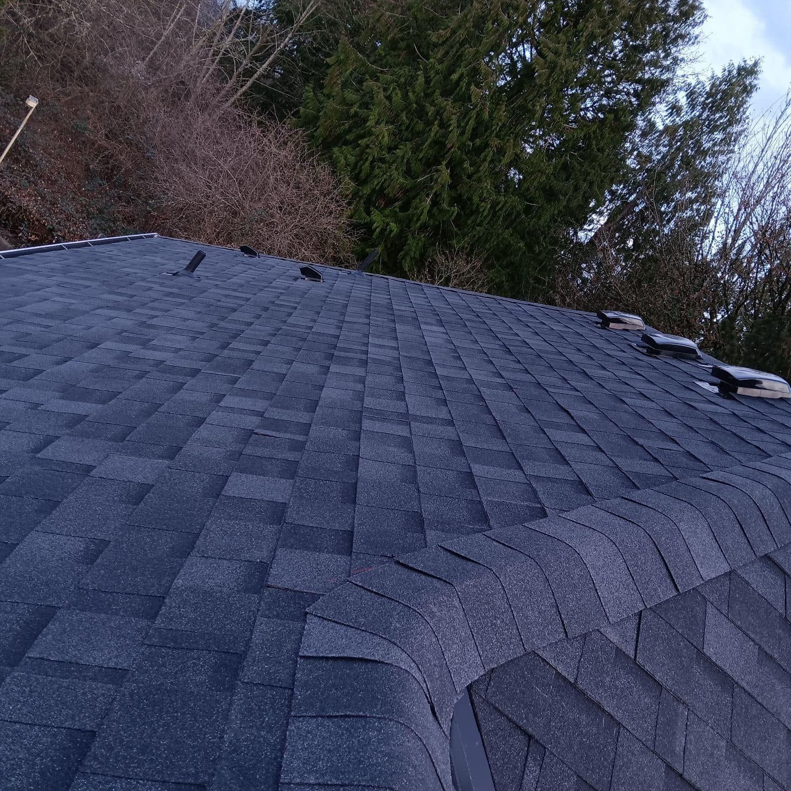 A roof with a lot of shingles on it and trees in the background.