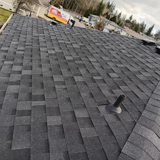 A roof with a lot of shingles on it and a truck in the background.