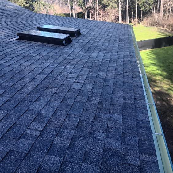 The roof of a house with two skylights on it.