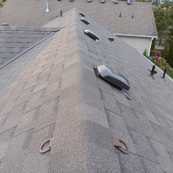 A roof with a lot of shingles and a skylight on it.