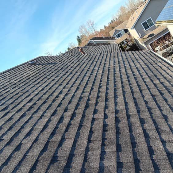 A roof with a lot of shingles on it and a house in the background.