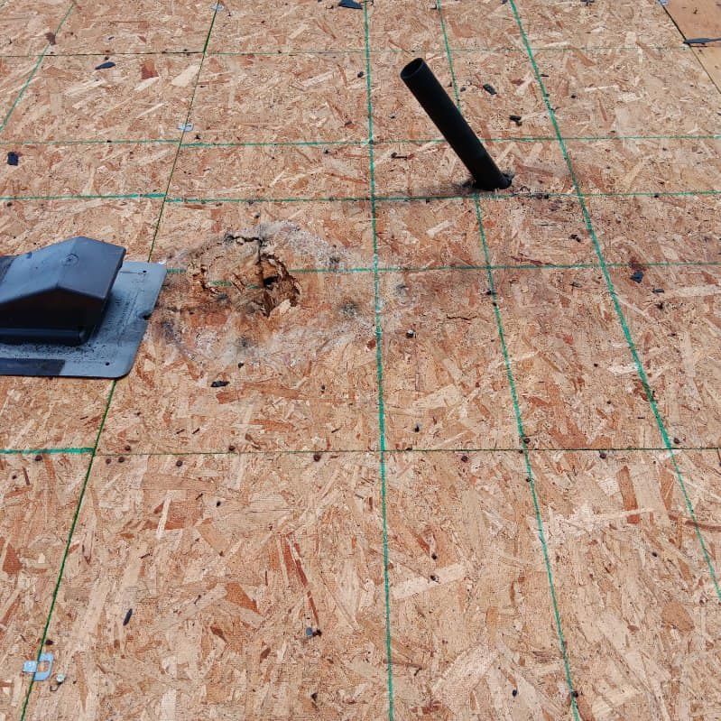 A roof with a hole in it and a vent on it.