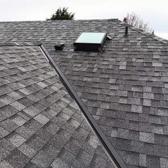 A roof with shingles and a skylight on it.