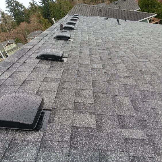 A roof with a lot of shingles and vents on it.