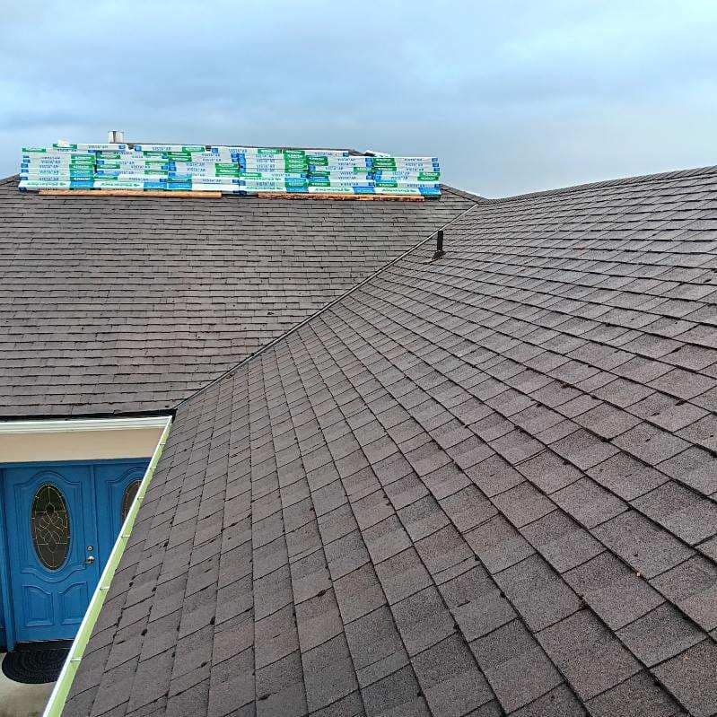 A roof with shingles on it is being installed on a house.