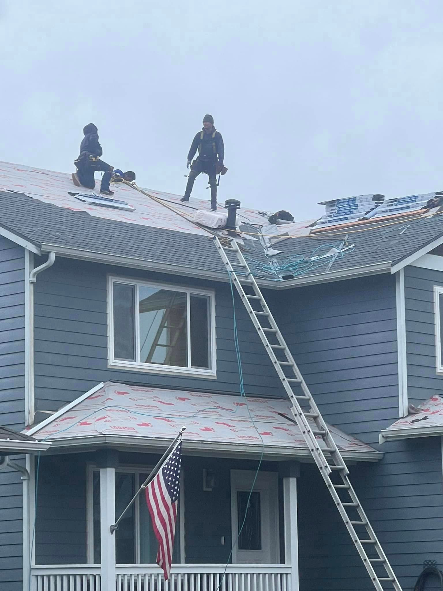 Two men are working on the roof of a house.