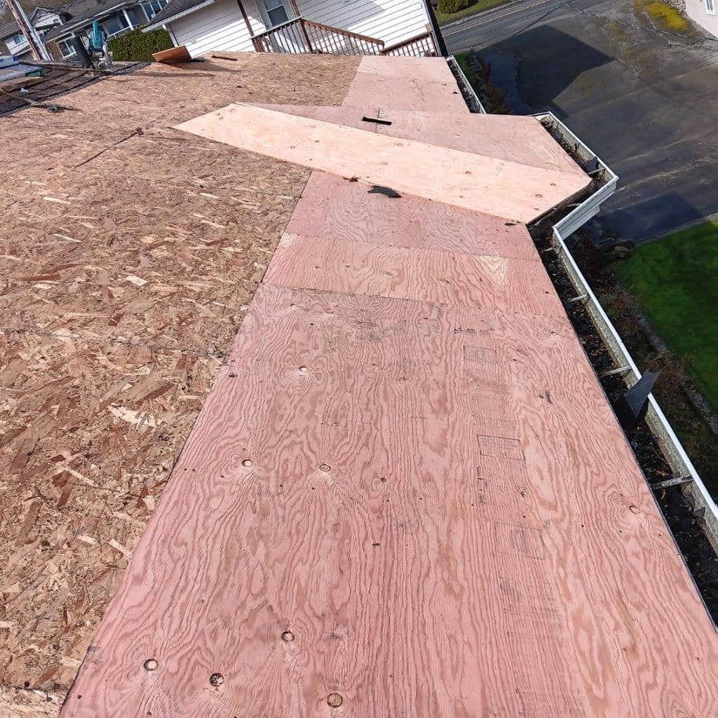 A large piece of plywood is sitting on top of a roof.