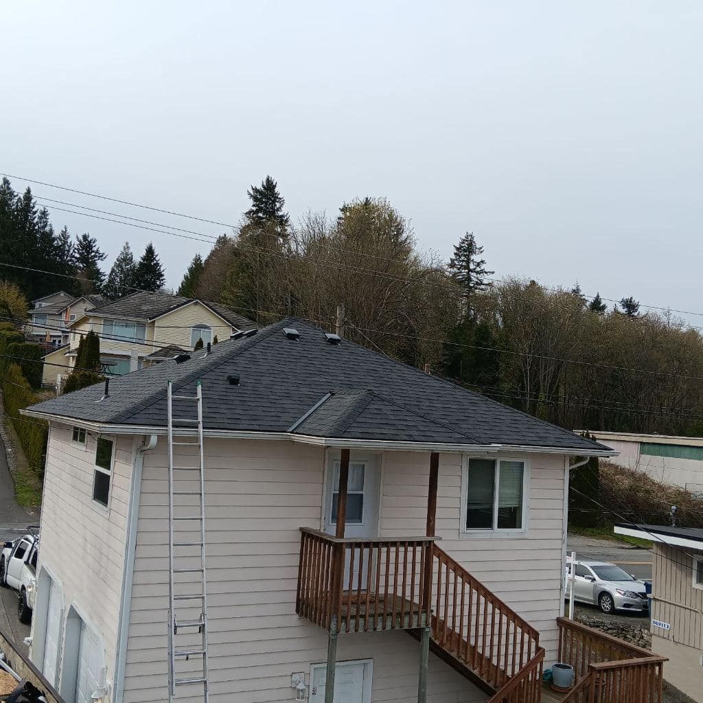 A white house with a black roof and stairs