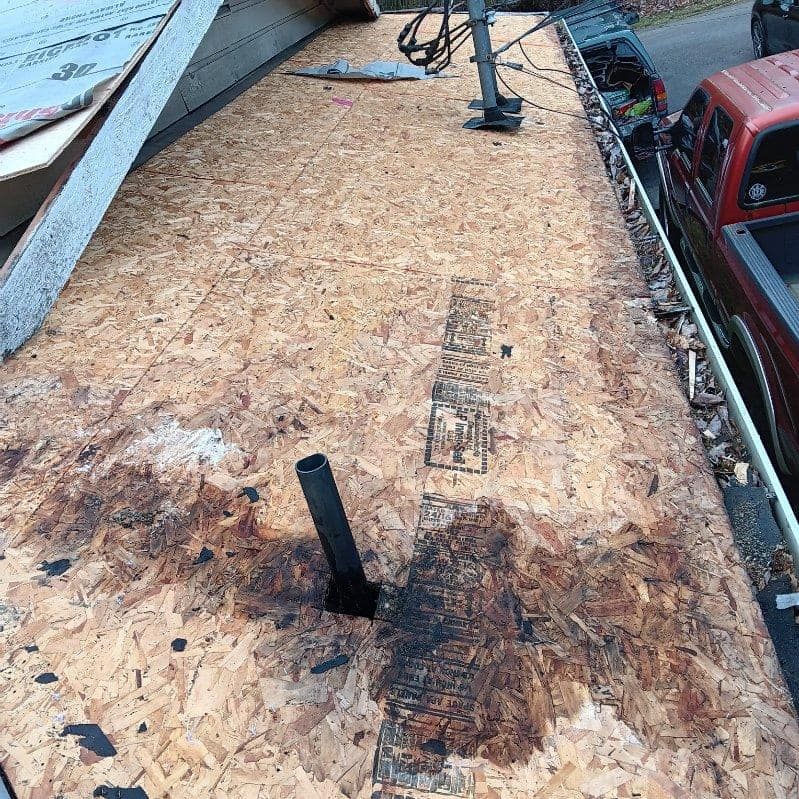 A roof with a hole in it and a truck parked next to it.