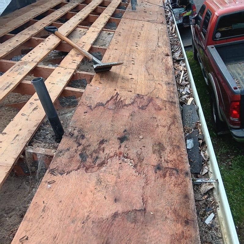 A red truck is parked next to a large piece of wood.