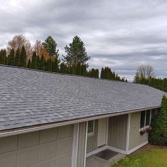 An aerial view of a house with a gray roof and trees in the background.