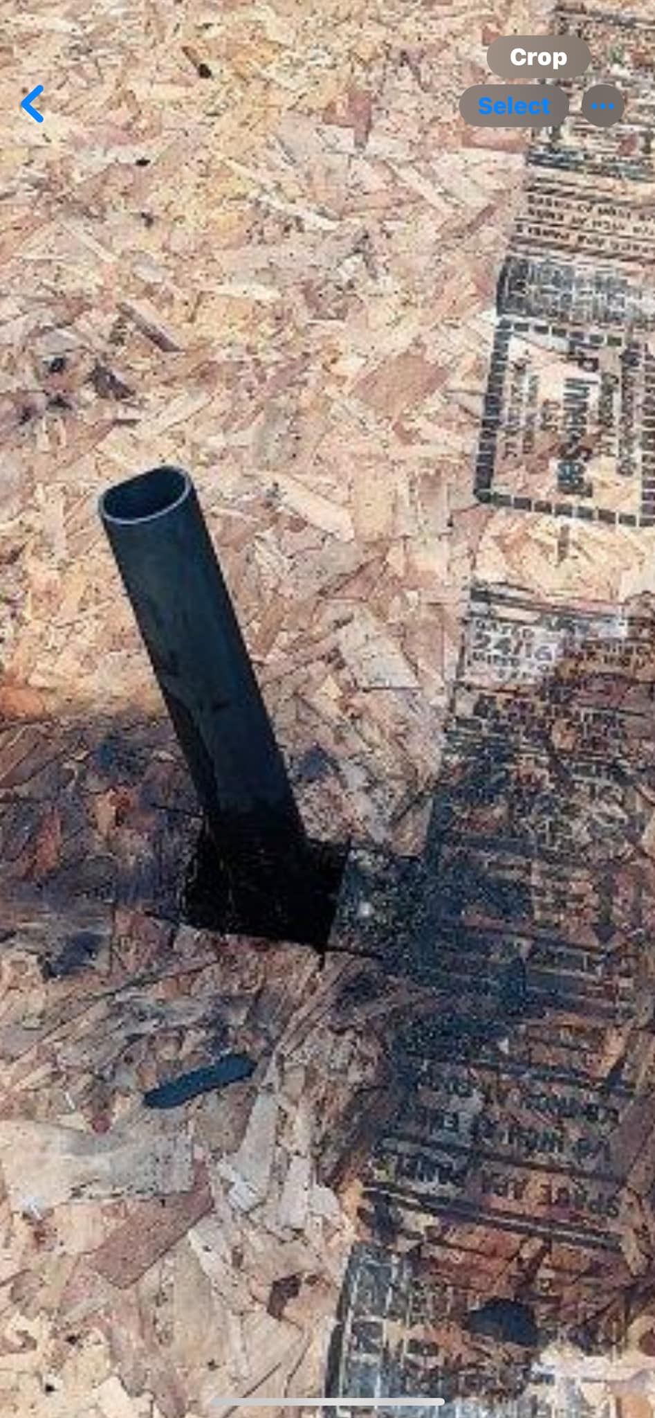 A black pipe is sticking out of a hole in the ground.