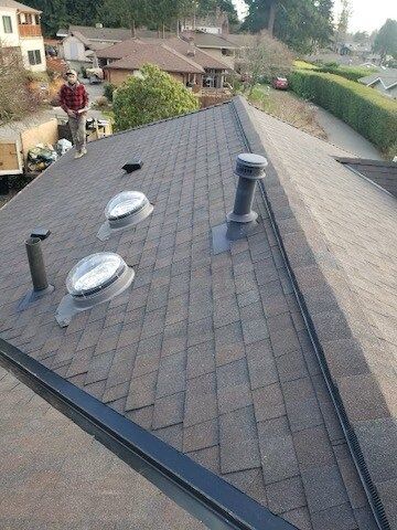 A man is standing on the roof of a house.