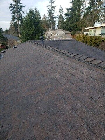 A roof with a lot of shingles on it and trees in the background.