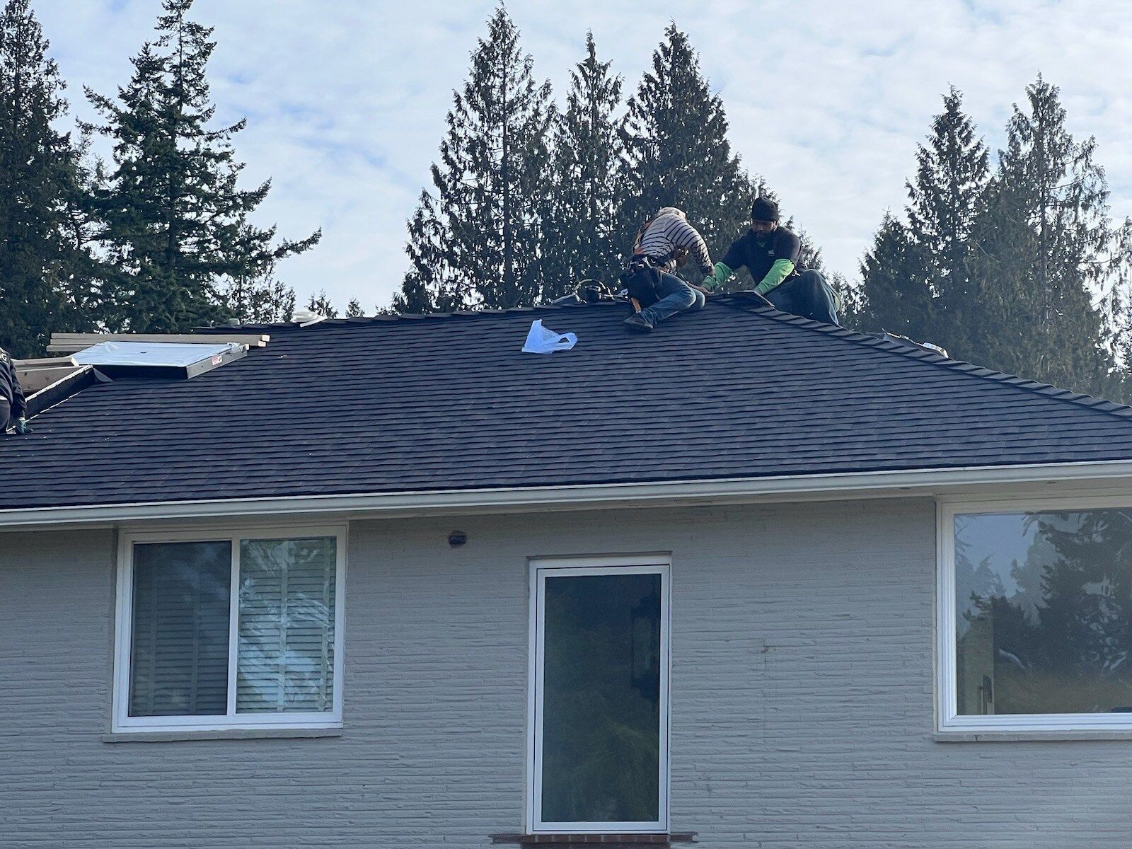 Two men are working on the roof of a house.