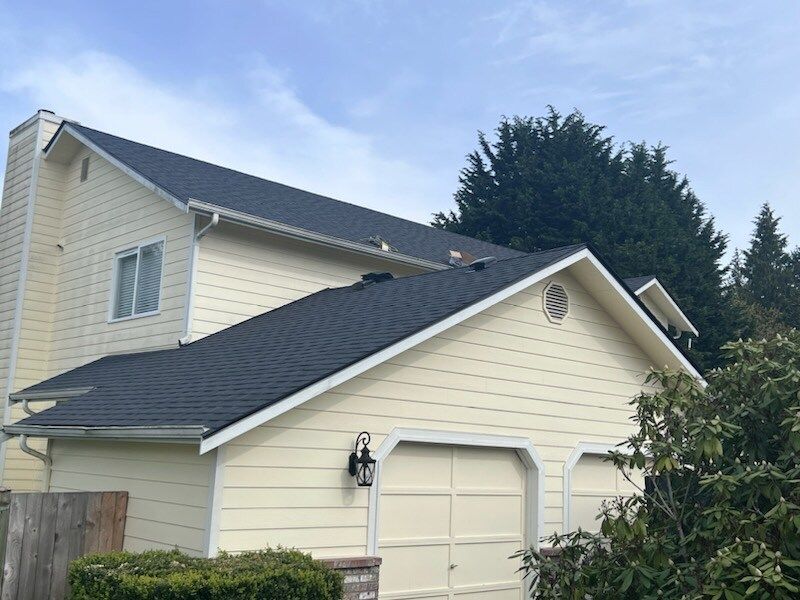 A white house with a black roof and a garage