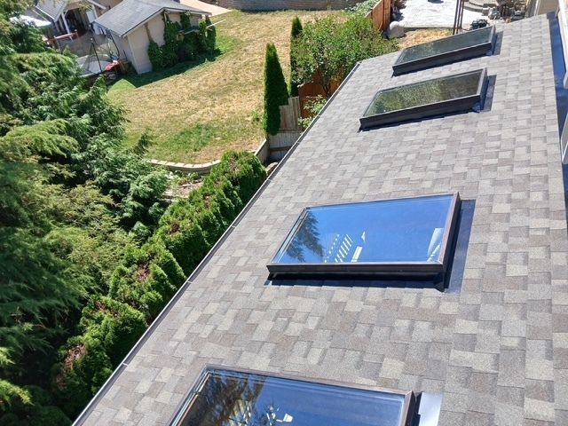 A roof with a chimney and a sunset in the background.
