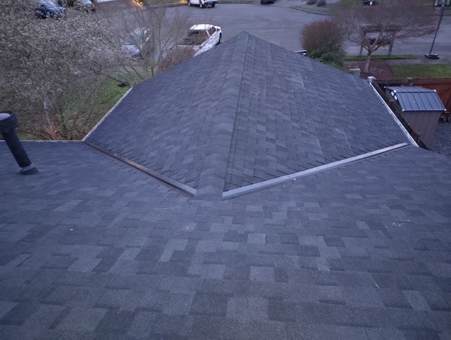 A roof with a skylight on it and a fence in the background.