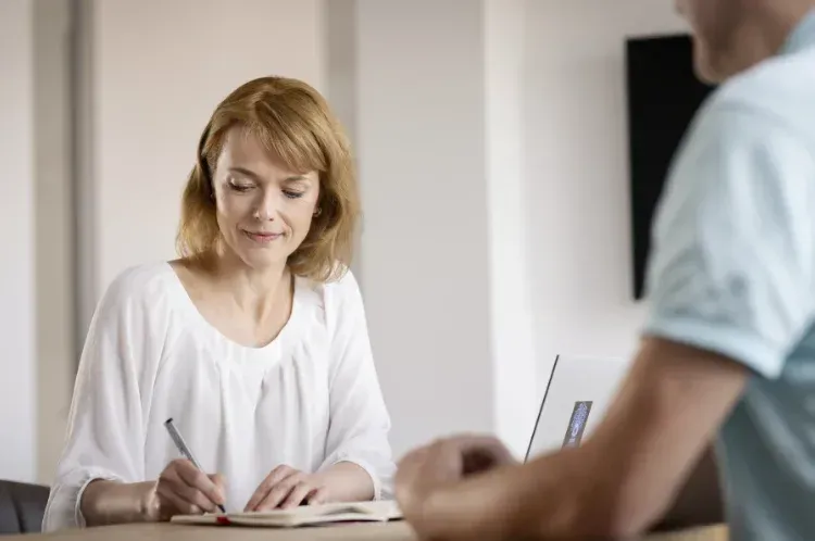 Porträtfoto im Gespräch mit Laptop, Notizbuch und Kugelschreiber, Foto: Bettina Engel-Albustin