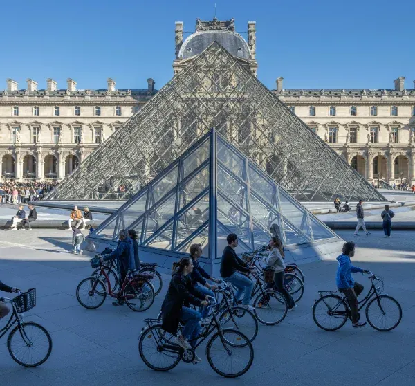 Menschen auf Fahrrädern auf dem Platz vor dem Pariser Louvre 