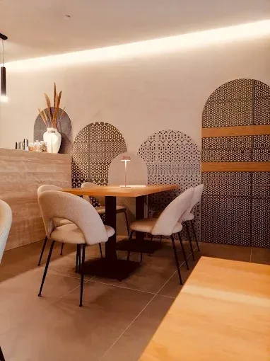 Interno di un ristorante con tavolo e sedie. La parete è decorata con pannelli decorativi e archi.