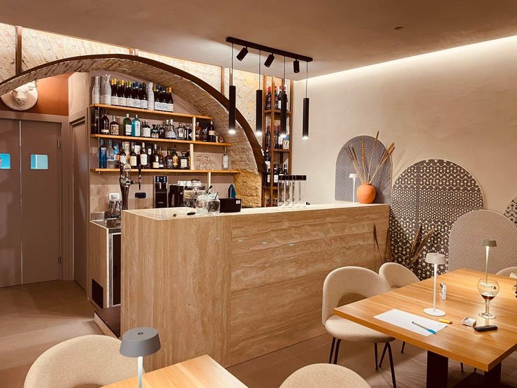 Interno di un ristorante moderno: tavoli, sedie, bancone, piante e lampade.