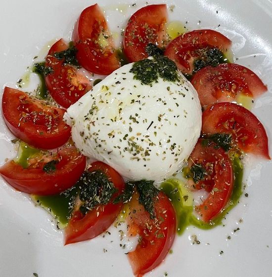 Interno di un ristorante moderno con tavoli, sedie e piante su pareti grigie e gialle.