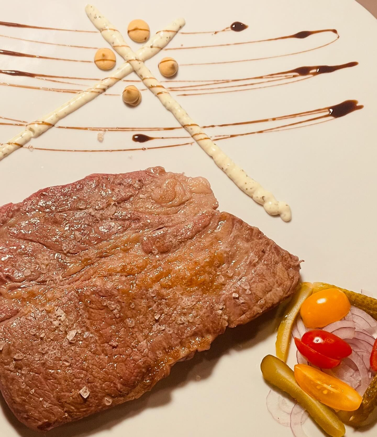 Interno di un ristorante moderno: tavoli, sedie, bancone, piante e lampade.