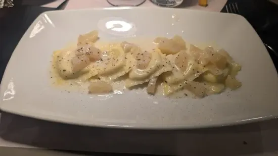 Pizza con formaggio, funghi e prezzemolo su un piatto bianco, con il logo del ristorante sullo sfondo.