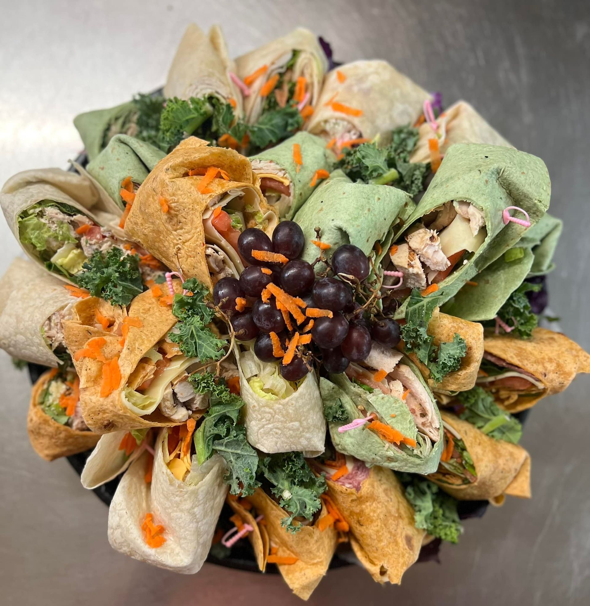 A bowl filled with wraps and grapes on a table.