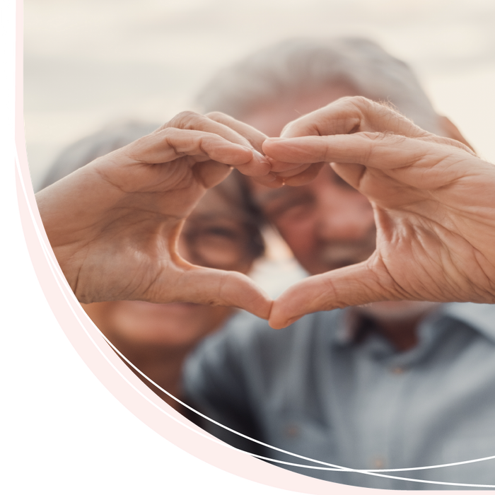 A man and woman are making a heart shape with their hands