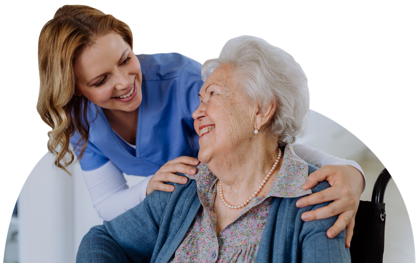 A nurse is putting her arm around an elderly woman in a wheelchair.