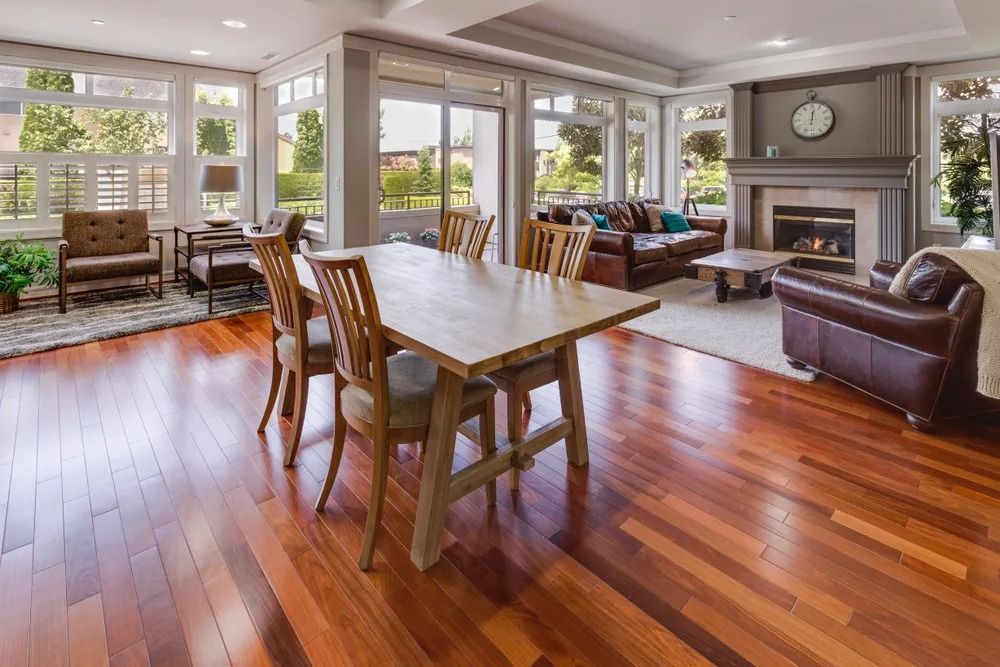 Bright open living room with wooden dining table, hardwood floors, fireplace, and leather chairs