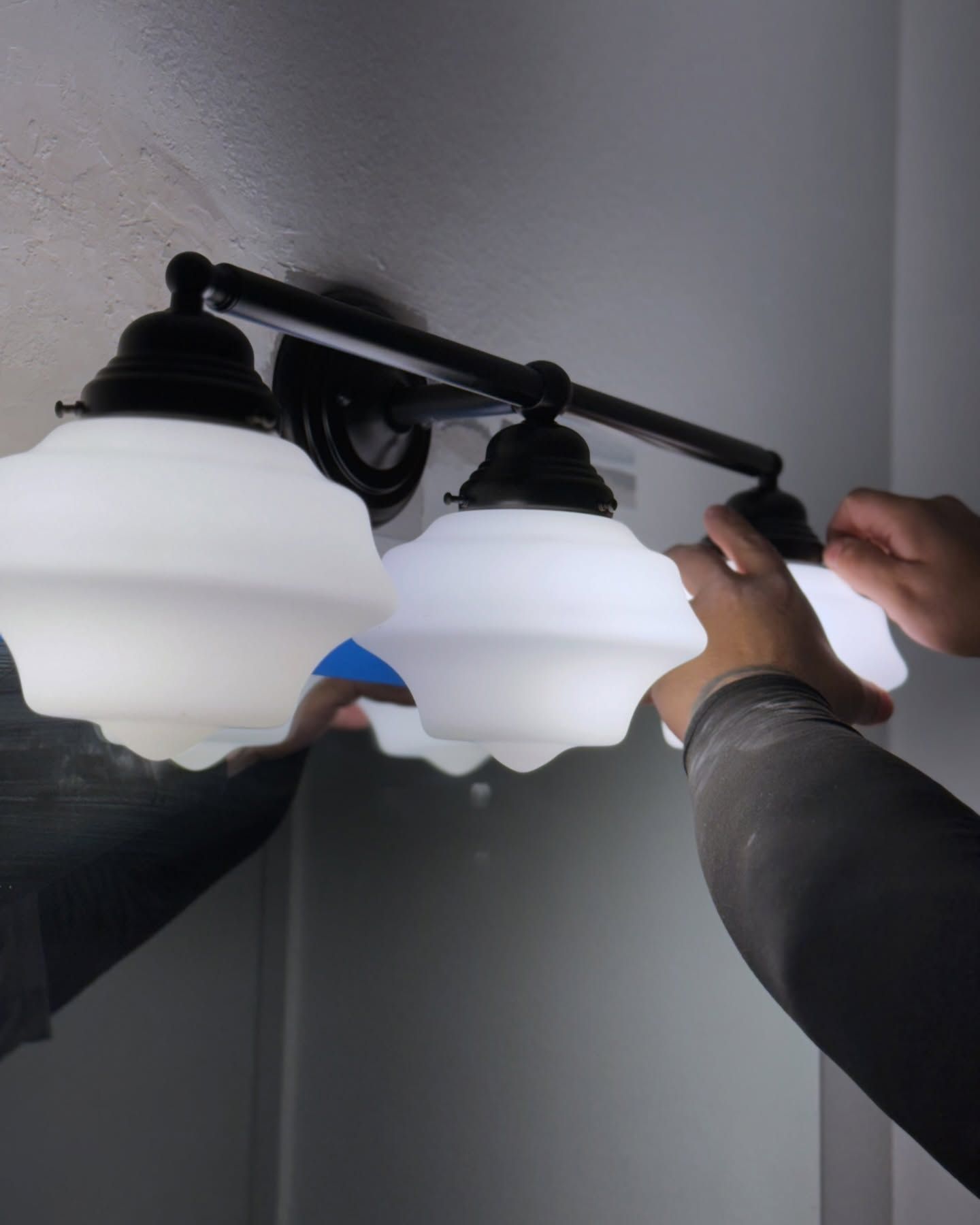 A person is fixing a light fixture in a bathroom