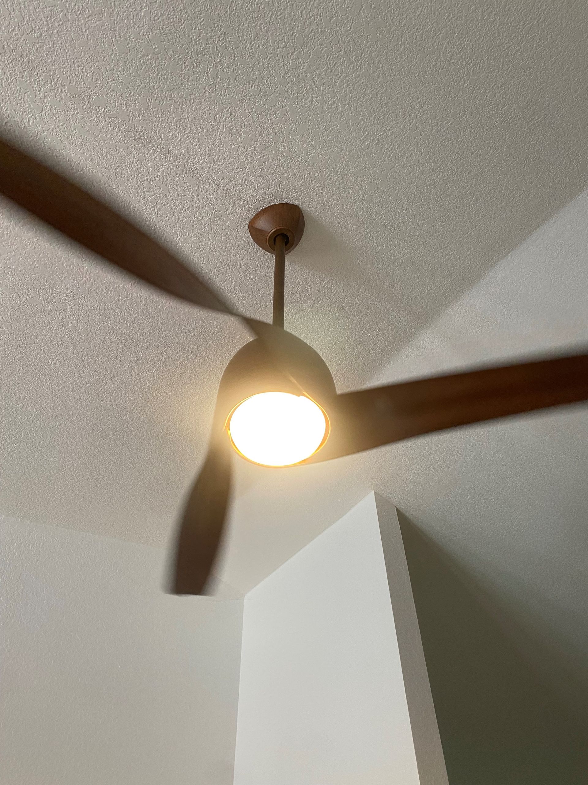 A ceiling fan with a light on it is hanging from the ceiling in a room.