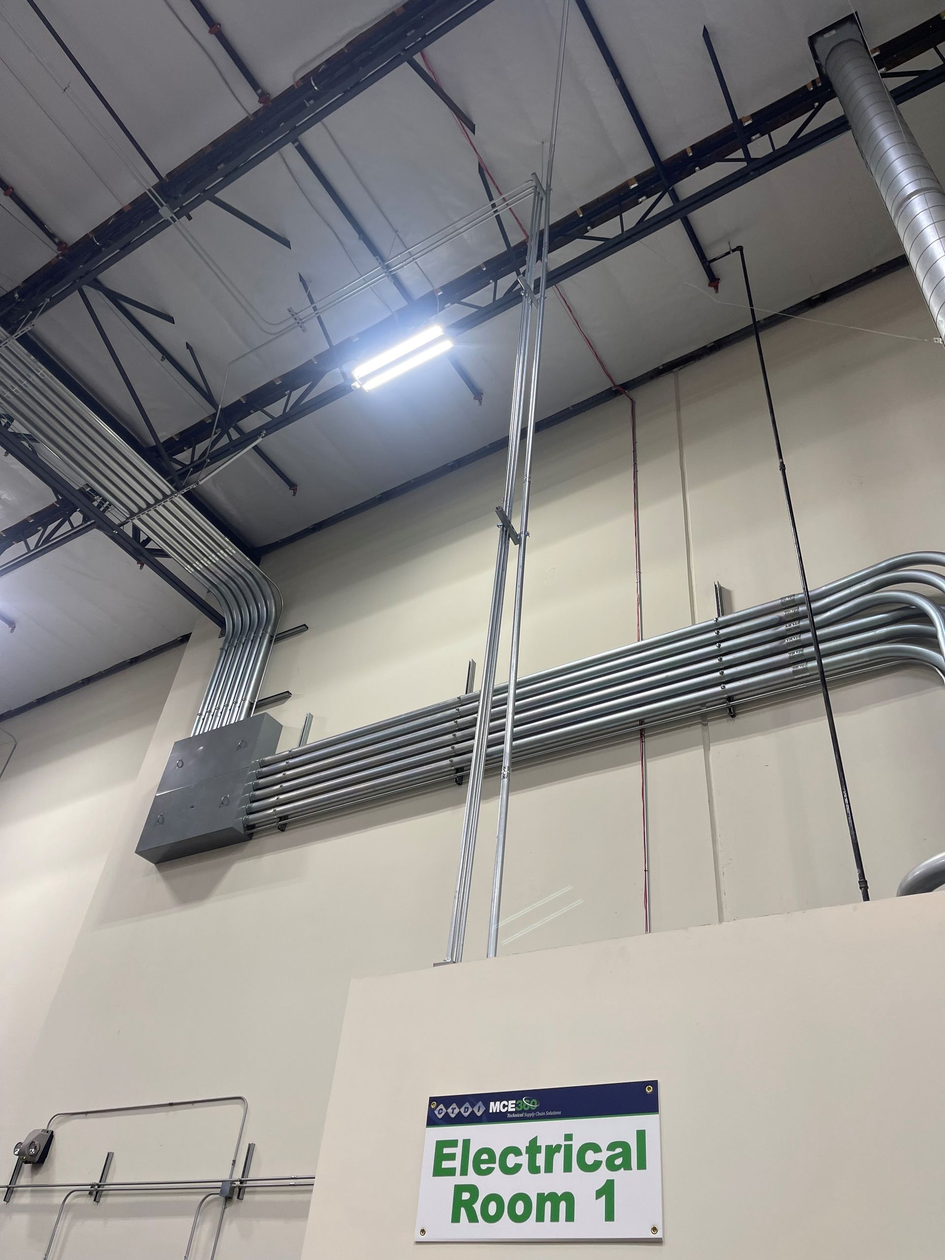 An electrical room sign hangs from the ceiling of a building