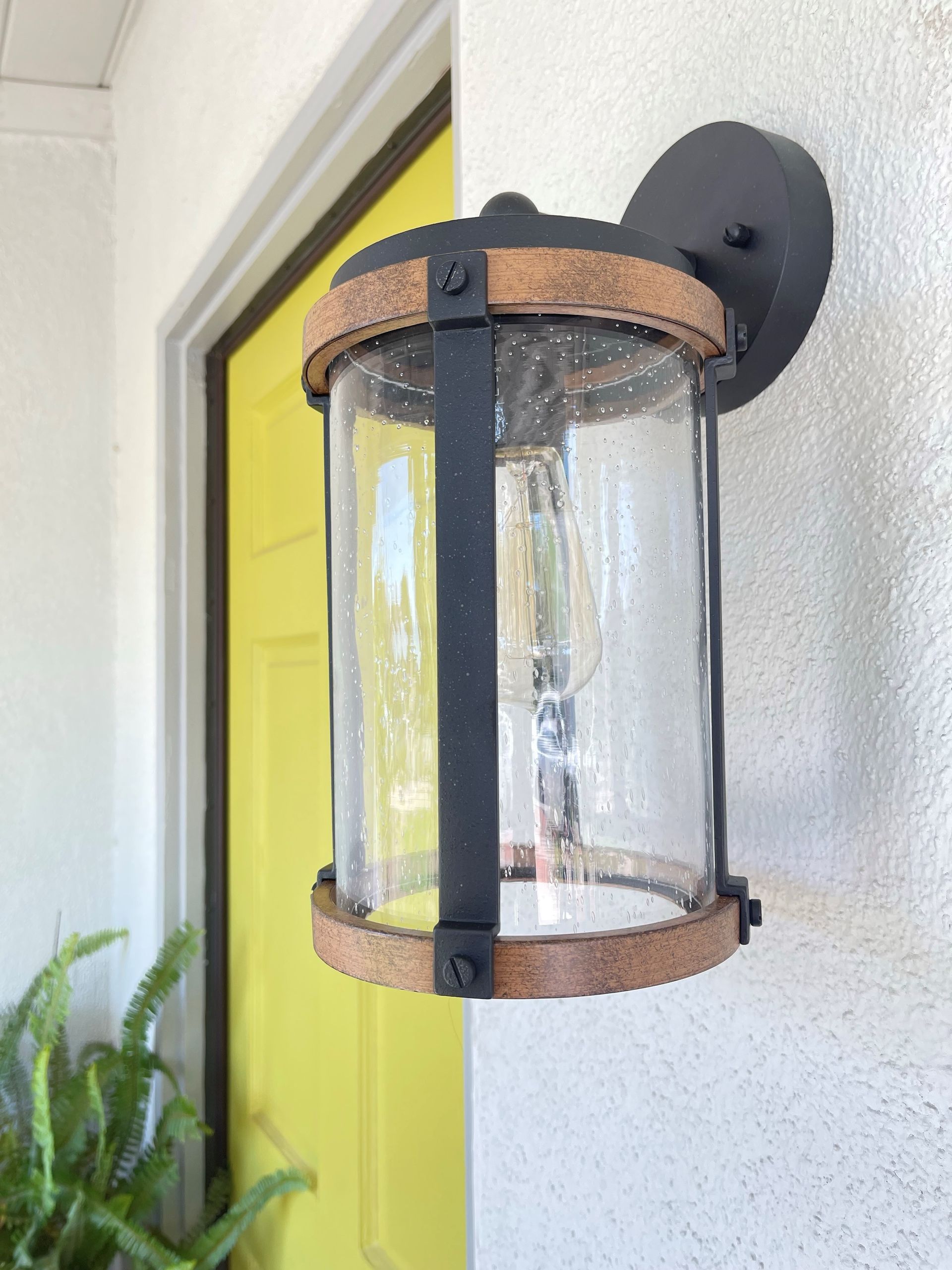 A light on the side of a building next to a yellow door